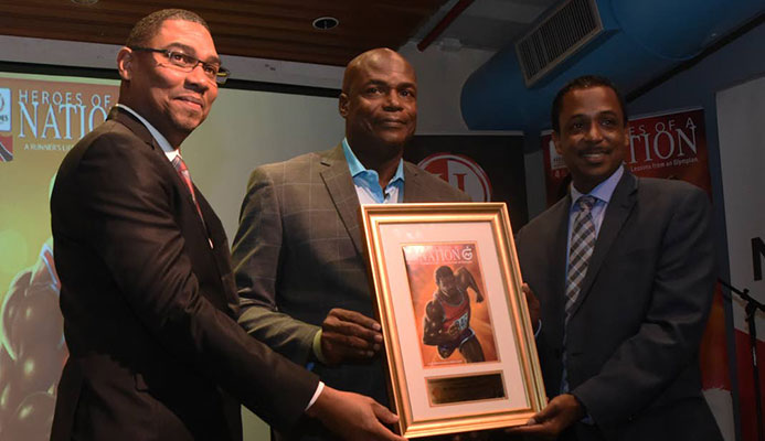 NGC’s vice president of operations Ronald Adams, left, and chairman of the Heroes Foundation Philip Julien, right, present Olympic 100m gold medallist Hasely Crawford with a framed copy of the first edition of the A Runner’s Life - Lessons from an Olympian, at National Library, Port of Spain, on Thursday. PHOTO BY KERWIN PIERRE NGC’s vice president of operations Ronald Adams, left, and chairman of the Heroes Foundation Philip Julien, right, present Olympic 100m gold medallist Hasely Crawford with a framed copy of the first edition of the A Runner’s Life - Lessons from an Olympian, at National Library, Port of Spain, on Thursday. PHOTO BY KERWIN PIERRE