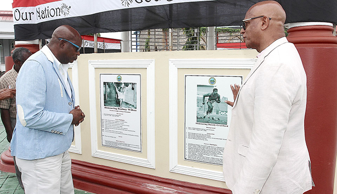 1976 Olympic Gold Medallist Hasely Crawford, left, view the Wall of Fame with San Fernando Mayor Junia Regrello after the unveiling ceremony at the Harris Promenade Bandstand in San Fernando, yesterday.  TONY HOWELL 1976 Olympic Gold Medallist Hasely Crawford, left, view the Wall of Fame with San Fernando Mayor Junia Regrello after the unveiling ceremony at the Harris Promenade Bandstand in San Fernando, yesterday.  TONY HOWELL