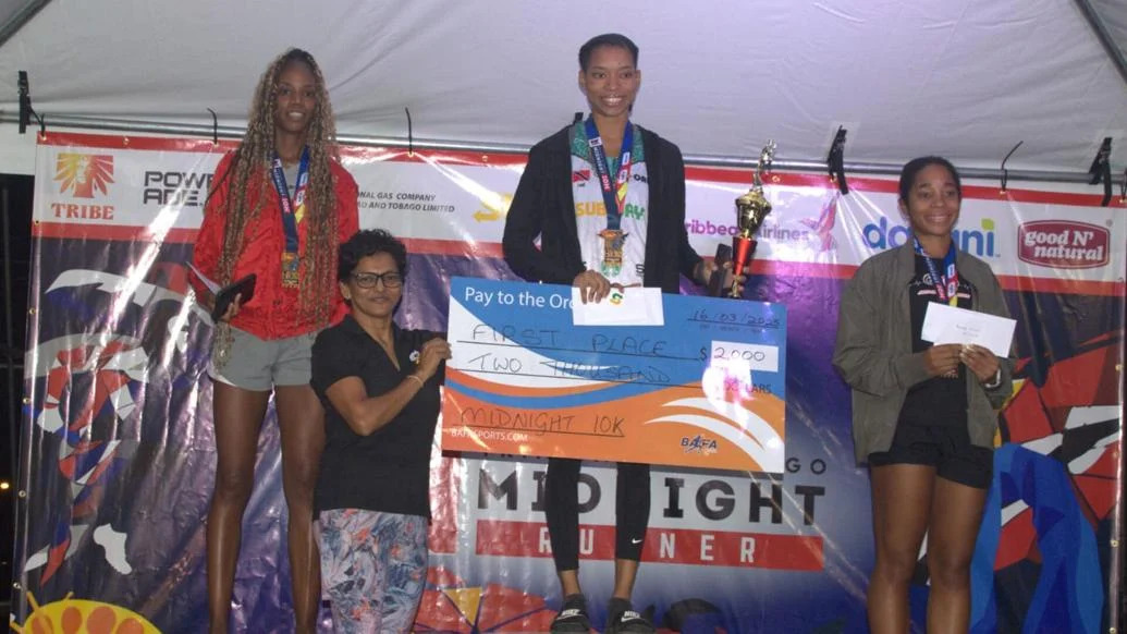 WOMEN’S WINNER: Alexia John collects her winner’s cheque after topping the women’s category in the Midnight 10k event, early Sunday morning at the Queen’s Park Savannah. April Francis, left, placed second while Zara Suite-Stewart finished third.  —Photo courtesy BAFA Sports (Image obtained at trinidadexpress.com) WOMEN’S WINNER: Alexia John collects her winner’s cheque after topping the women’s category in the Midnight 10k event, early Sunday morning at the Queen’s Park Savannah. April Francis, left, placed second while Zara Suite-Stewart finished third.  —Photo courtesy BAFA Sports (Image obtained at trinidadexpress.com)