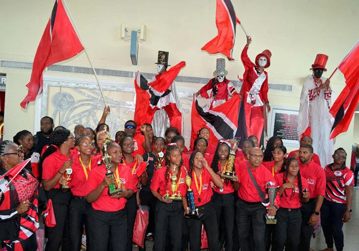 TIME TO CELEBRATE: Members of the Trinidad and Tobago Under-16 netball team, their coaches and technical staff enjoy the moment at Piarco International Airport yesterday, after returning home with the trophy for winning the 21st Jean Pierre Youth Championship in Barbados. —Photo: JERMAINE CRUICKSHANK (Image obtained at trinidadexpress.com)